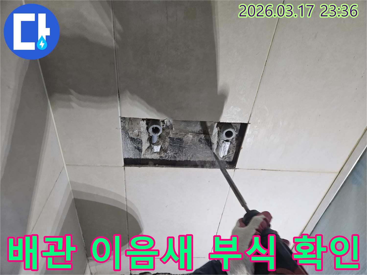 누수 지점을-찾기 위해-타일이 제거된-벽면에서-배관 이음새의-부식 여부를-육안으로-점검하는-모습입니다