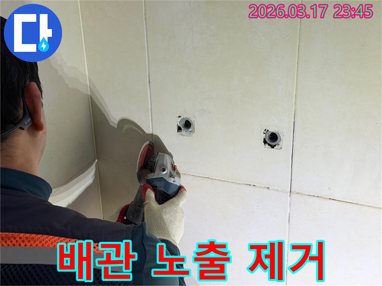누수된 배관을-노출시키기 위해-전문가가-타일 벽면을-그라인더로-조심스럽게-제거하고-있습니다