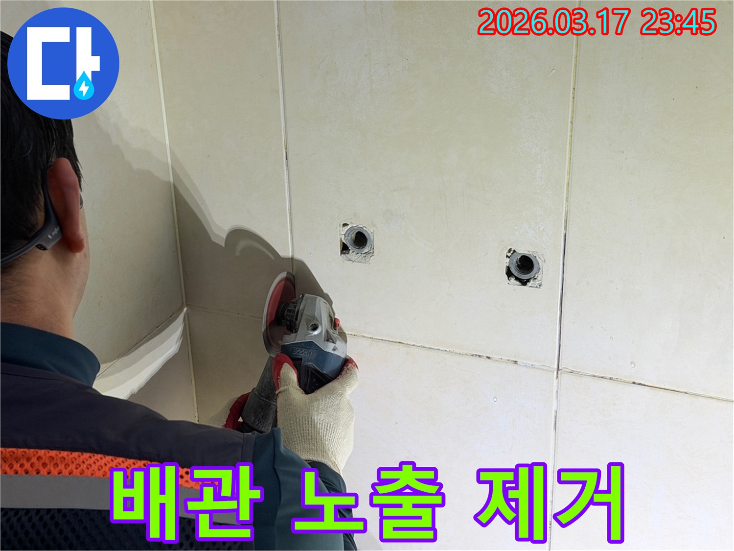 누수된 배관을-노출시키기 위해-전문가가-타일 벽면을-그라인더로-조심스럽게-제거하고-있습니다