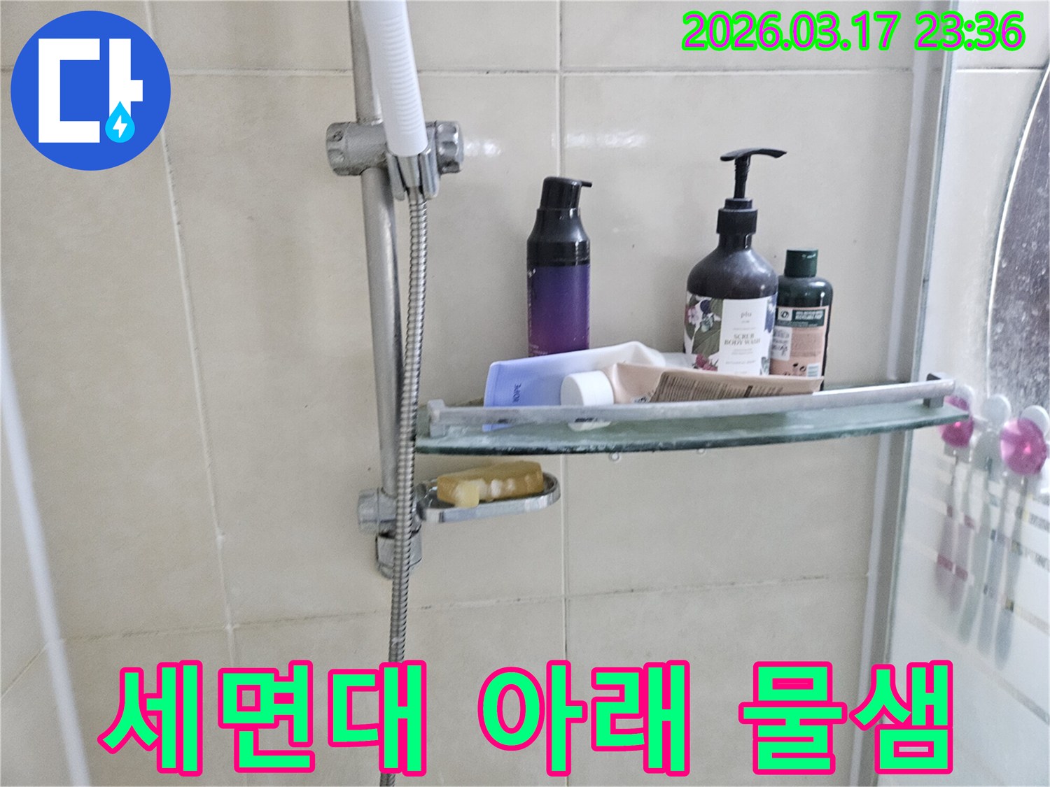 화장실 샤워기 옆-유리 선반에 맺힌 물방울은-세면대 아래 물샘의 간접적인 증거를 보여주는 이미지입니다