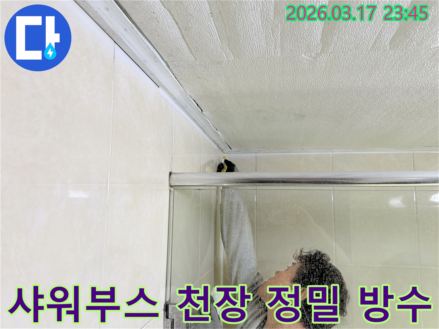 화장실 샤워부스 상단-천장 접합부에서 발생한 누수 문제를 해결하기 위해-실리콘 보수 작업을 진행하는 전문가의 모습입니다.