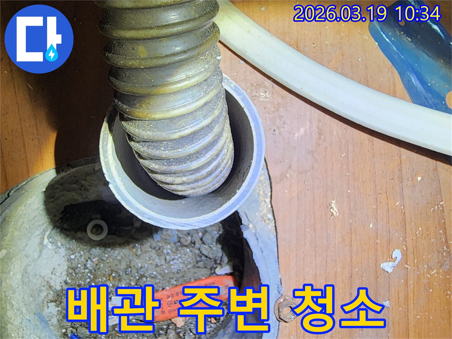 이 이미지는-서울 성동구의-누수 현장에서-배관 주변을-깨끗하게 청소하고-정리하는 작업을-보여줍니다