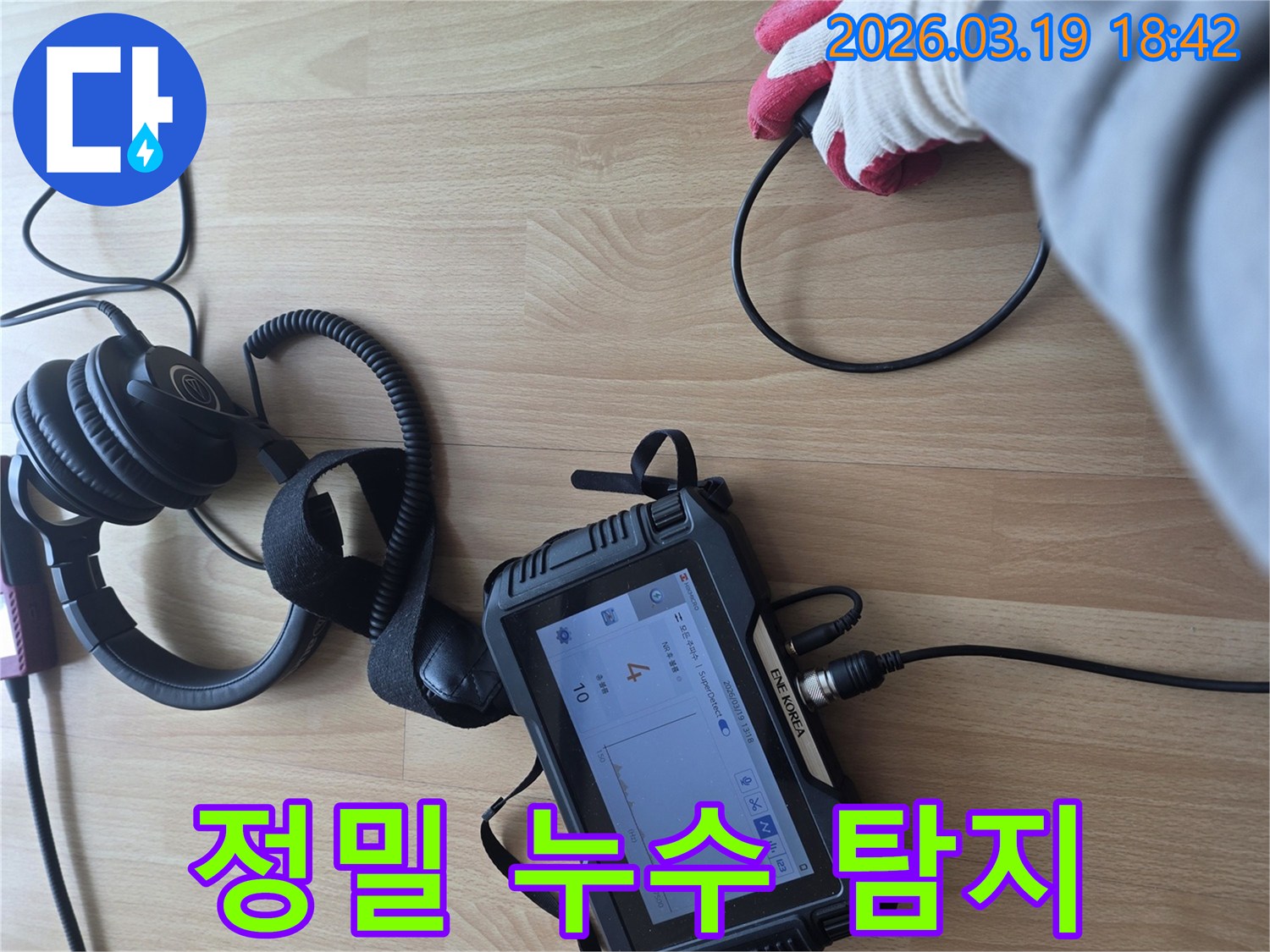 누수 탐지 전문가가-바닥에 놓인 장비와 헤드폰을 이용해-미세한 누수음을 듣고-누수 지점을 정확히 파악하는-현장 작업 모습입니다