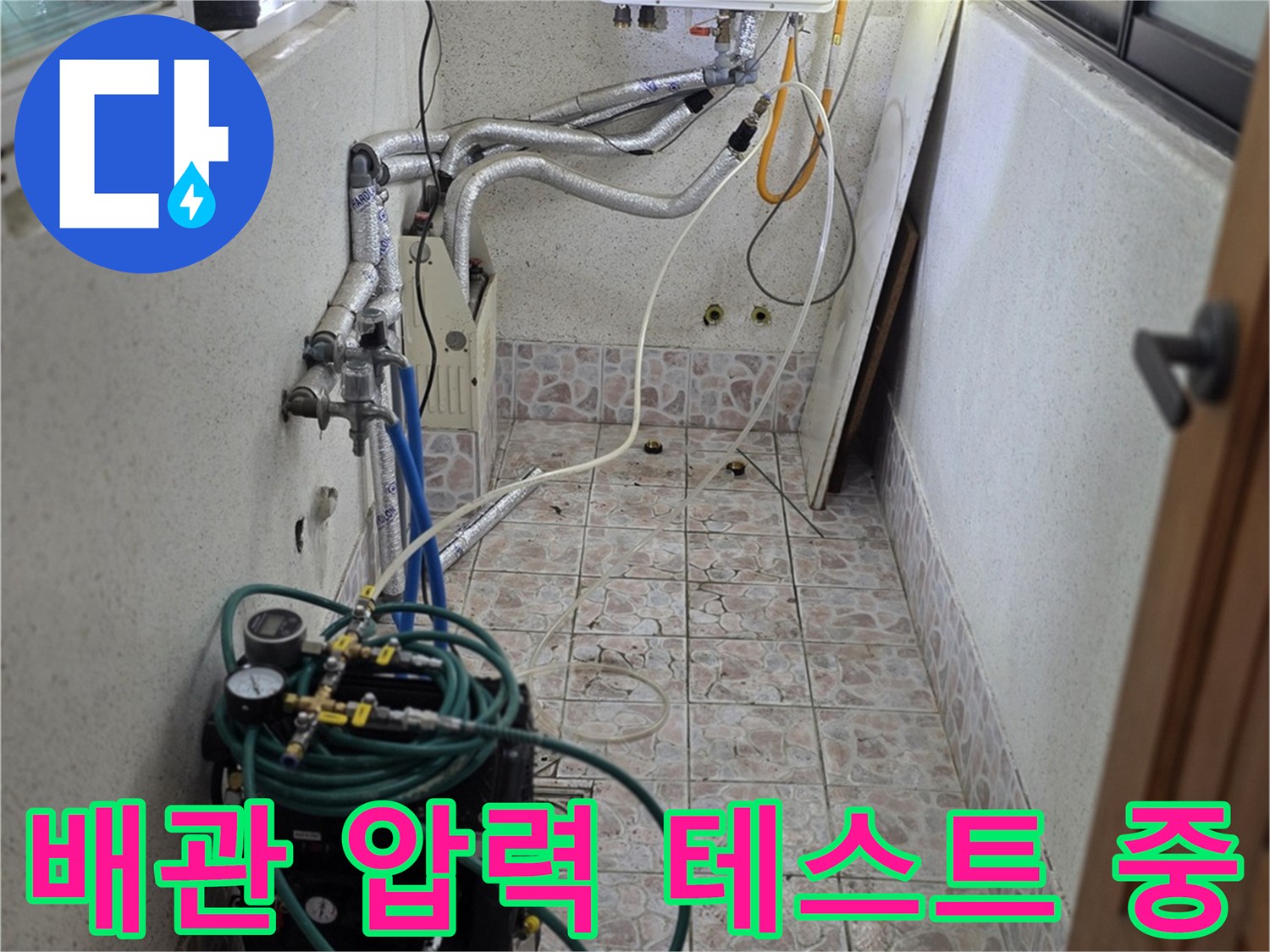 보일러실 벽면 타일 부근에 연결된 공압 측정 장비와 호스