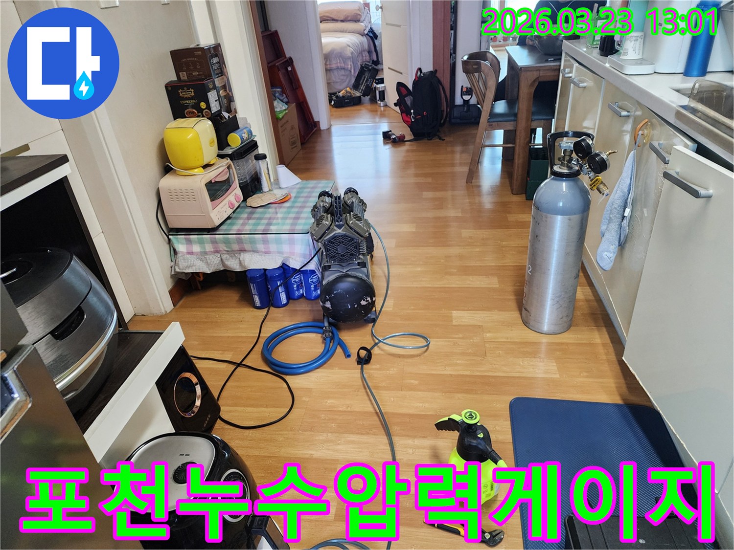 아파트 내부에서 누수 탐지를 위해-압력 게이지가 부착된 장비와 가스 실린더를 설치하고-검사를 준비하는 모습