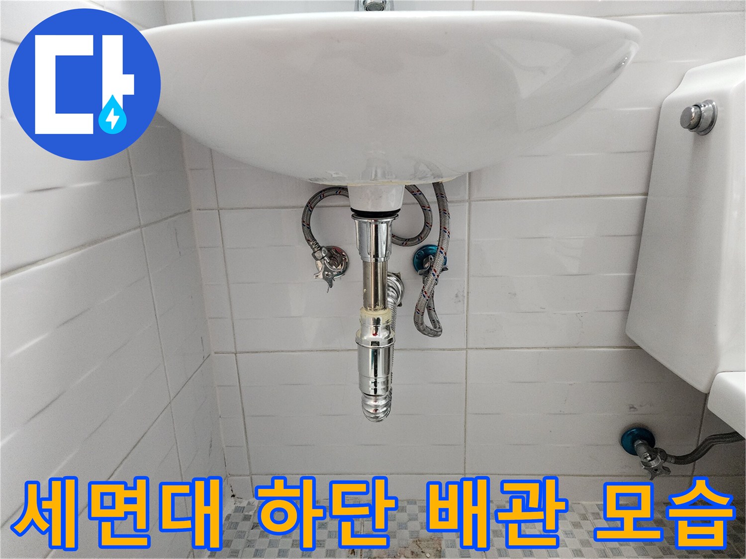 화장실 세면대 아래에 연결된 은색 수도 배관과 밸브의 상태를 보여주는 사진입니다.