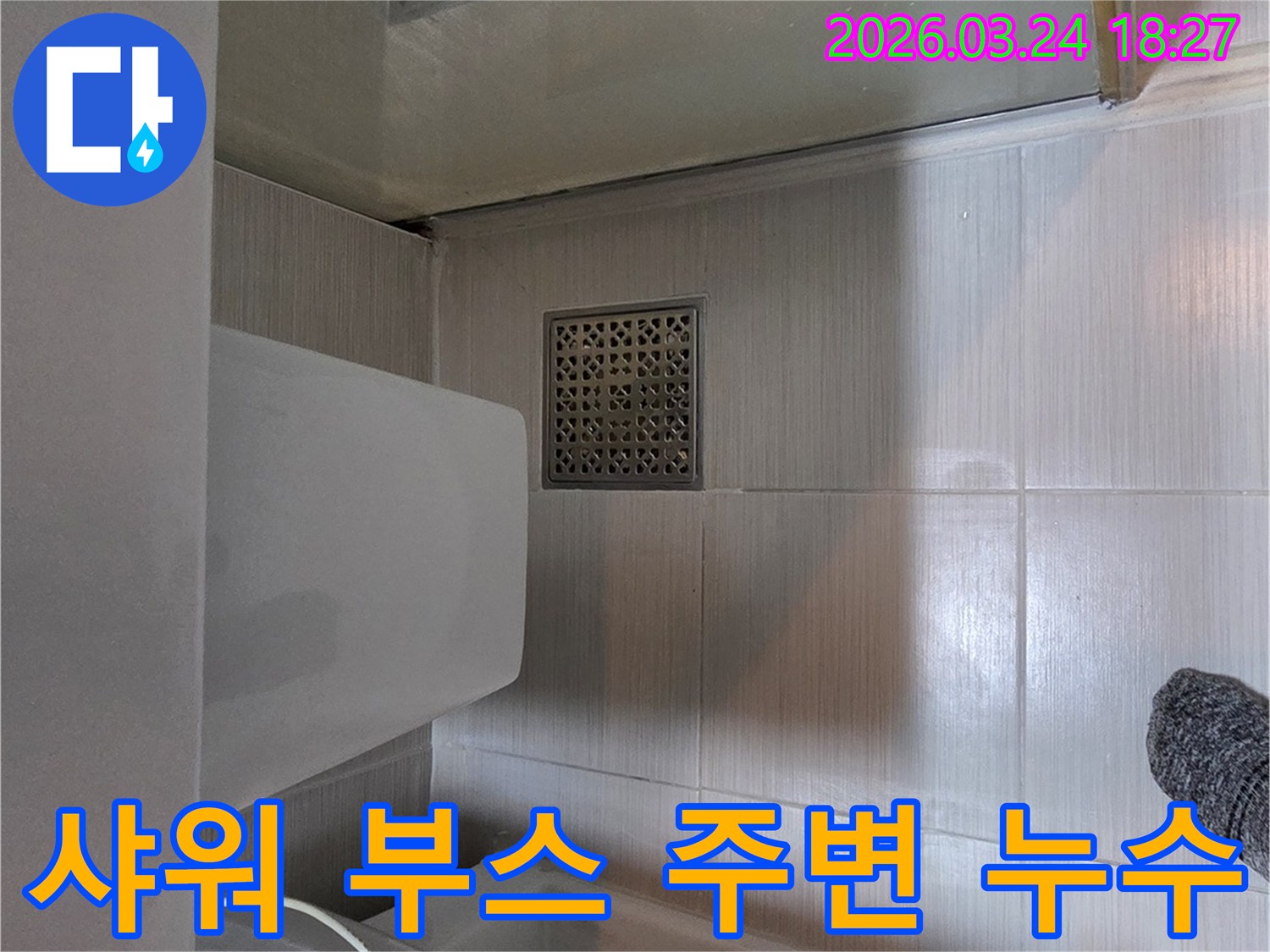 동두천시 욕실에서-샤워 부스 경계면과 바닥 타일 주변의-물 스밈 현상을 확인하며-누수 원인을 파악하는-전문가의 현장 점검 사진입니다.