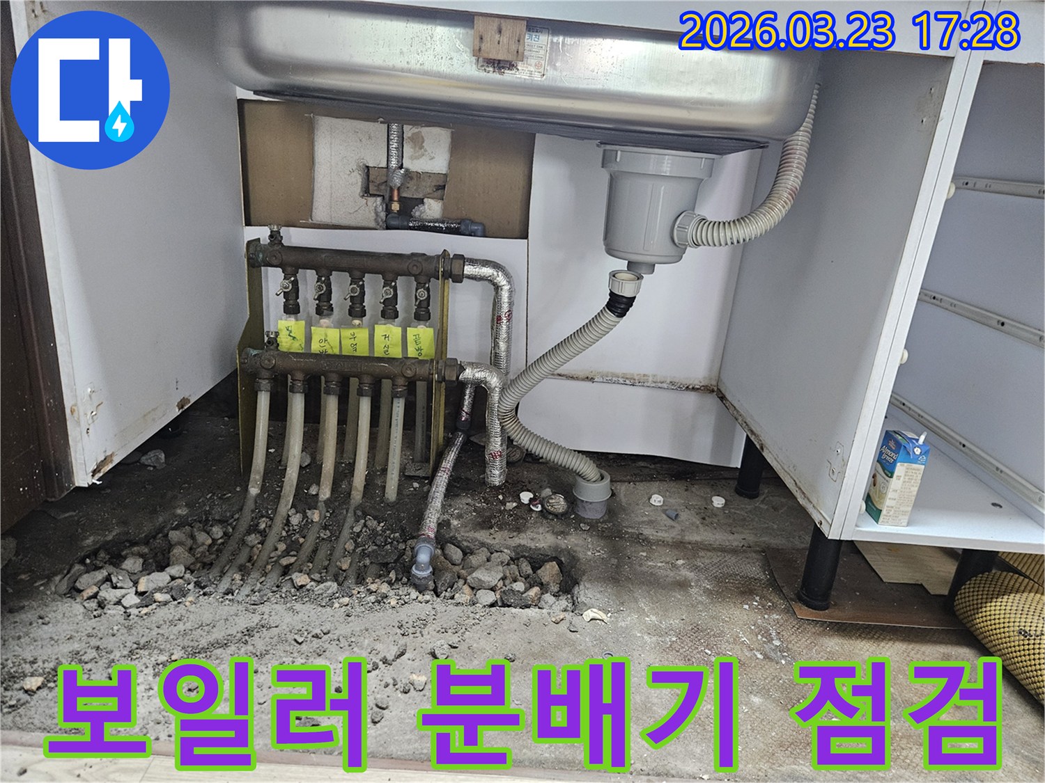 싱크대 하부 보일러 분배기 주변에서 발생한 누수를 점검하고-수리 계획을 세우는 현장 모습입니다.
