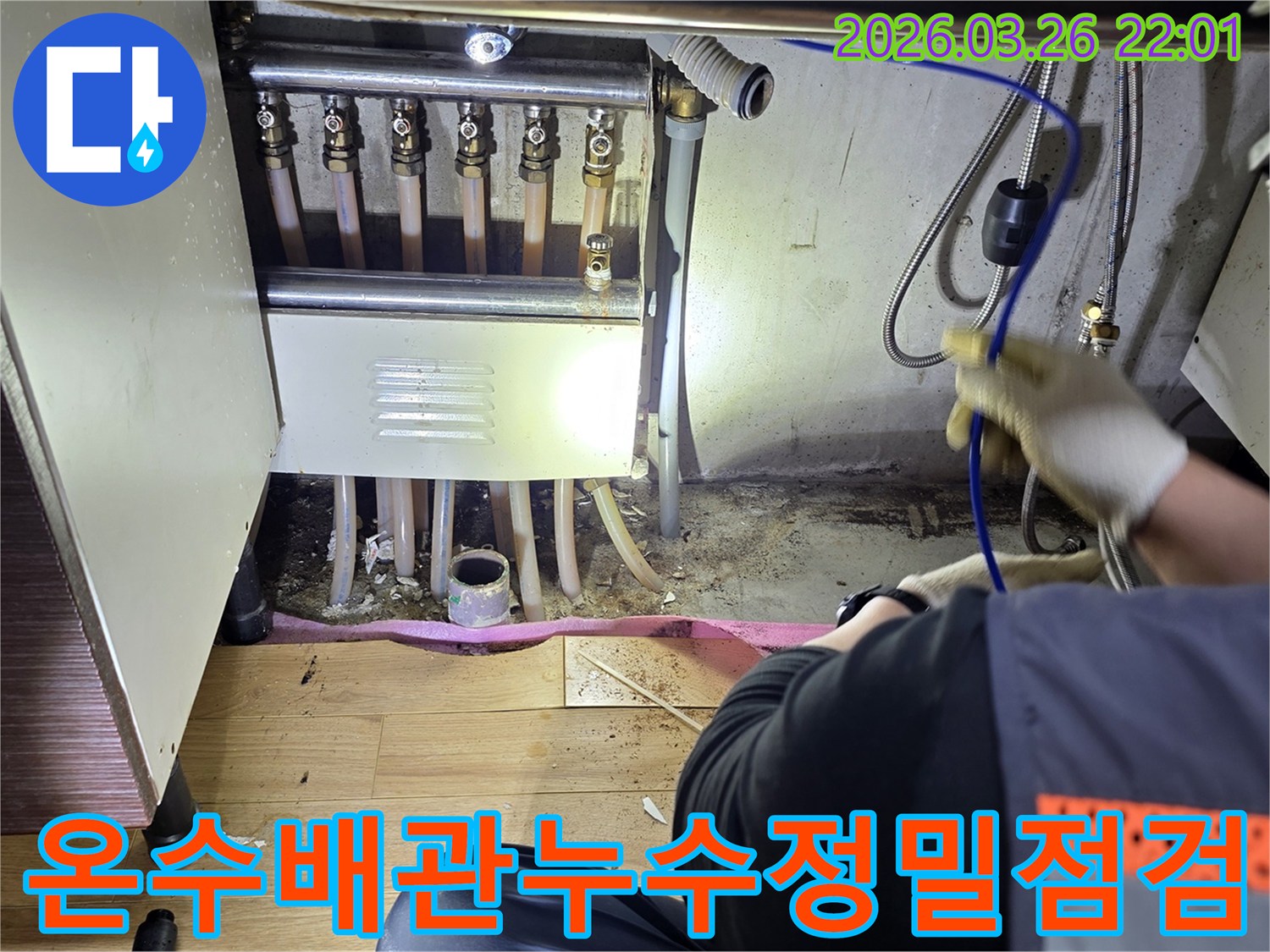 누수-엔지니어가-온수-배관-분배기-아래-누수-현장을-정밀하게-점검하는-모습