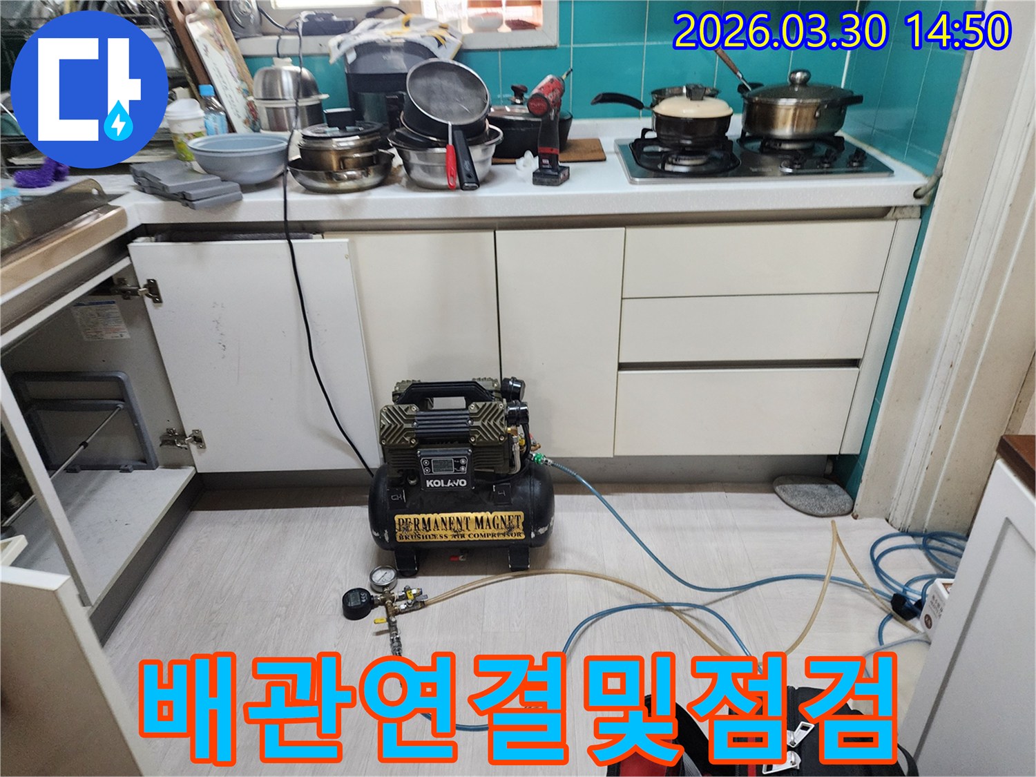 주방 하부장 아래에서-누수 탐지용 공압 장비와 배관이-정밀하게 연결되어-압력 테스트를 준비하는 모습입니다.