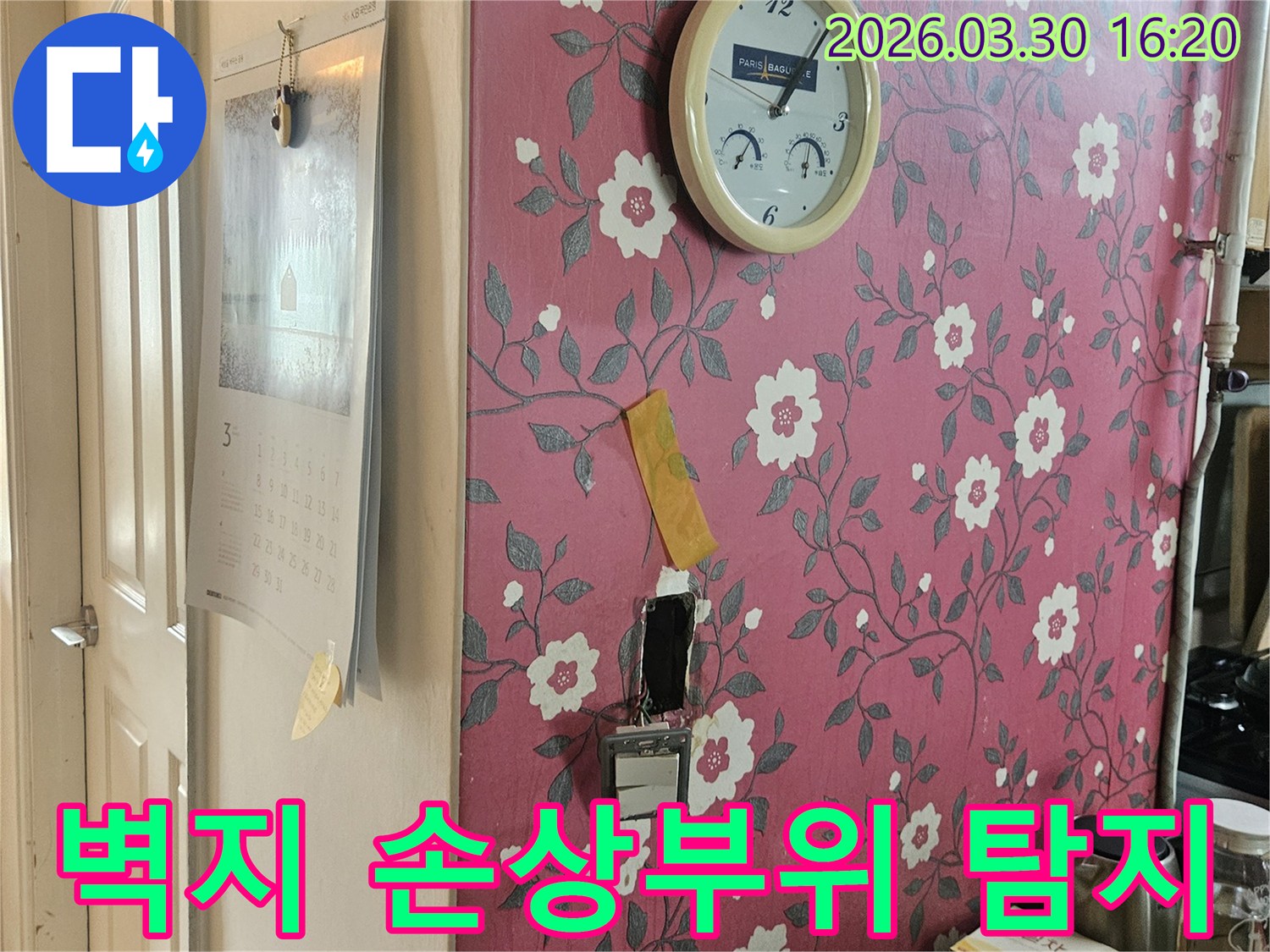 분홍색 꽃무늬 벽지에-시계가-있고-누수-탐지를-위해-벽면이-개방된-부분-주변을-정밀하게-점검하는-사진입니다