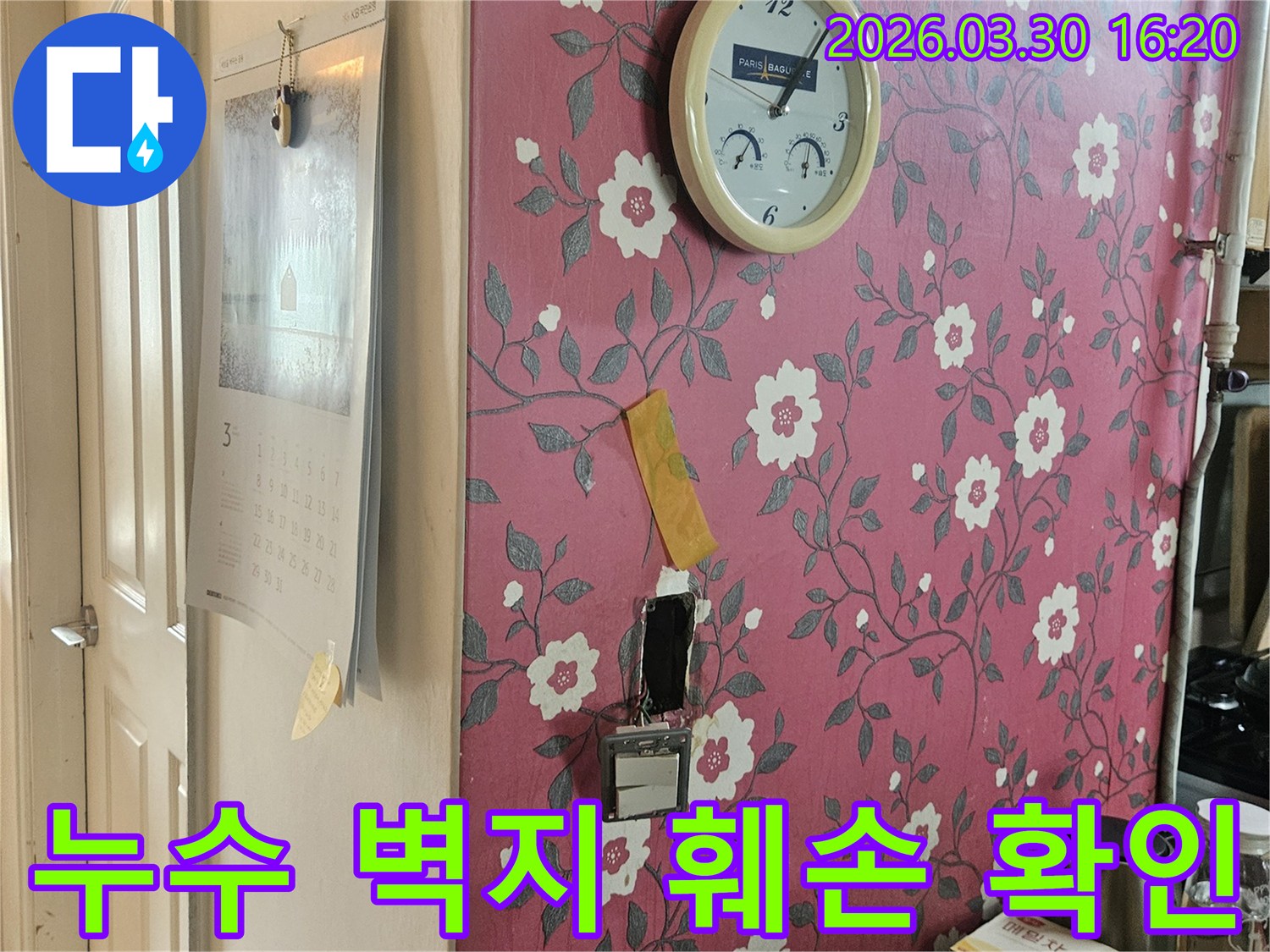 분홍색 꽃무늬 벽지에-시계와-함께-누수-탐지를-위해-뜯어낸-벽면-일부가-보이는-현장-사진입니다