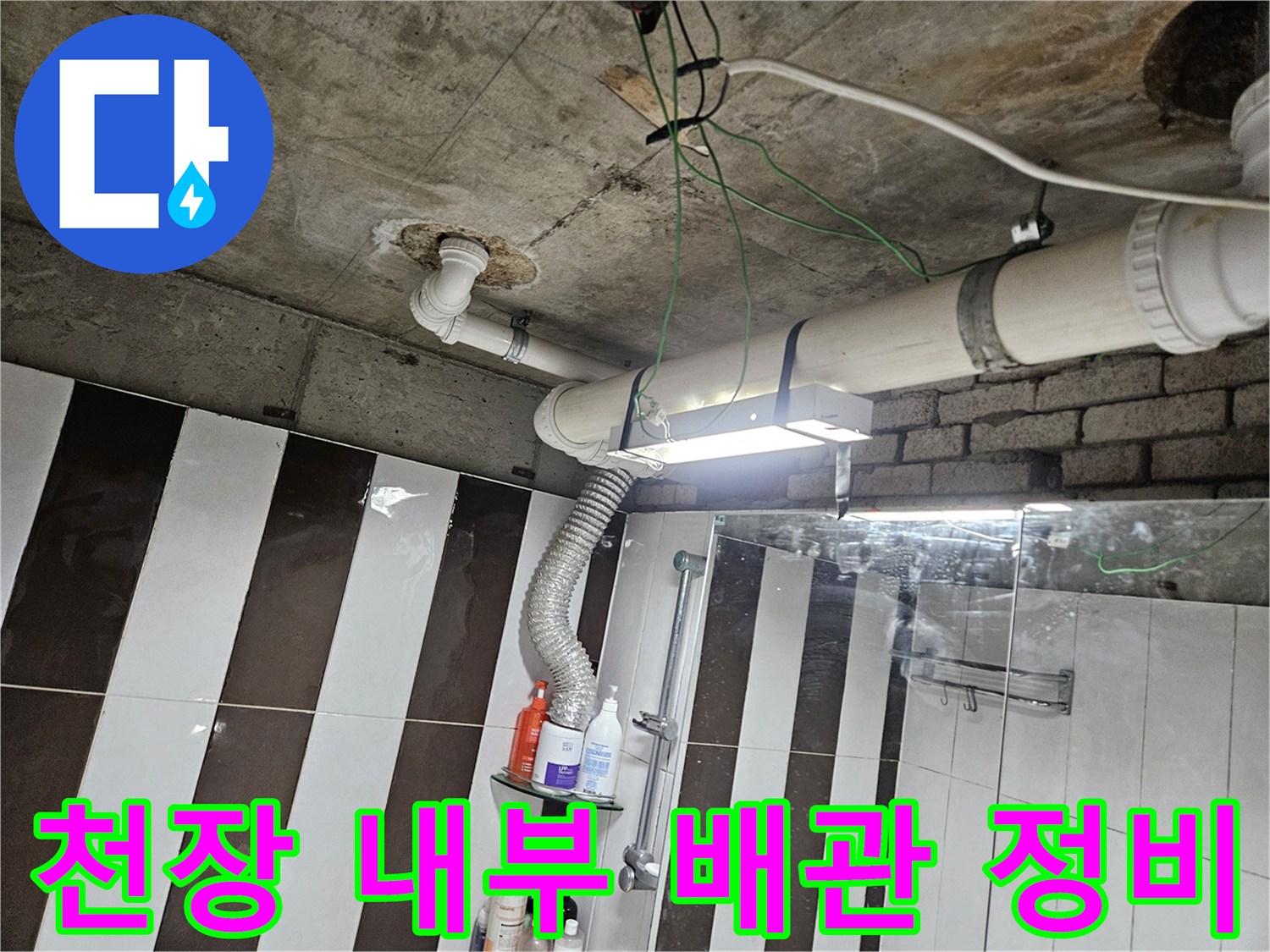 흰색 PVC 배관과 은색 자재가 연결된 천장 배관 구조를 보여줍니다.