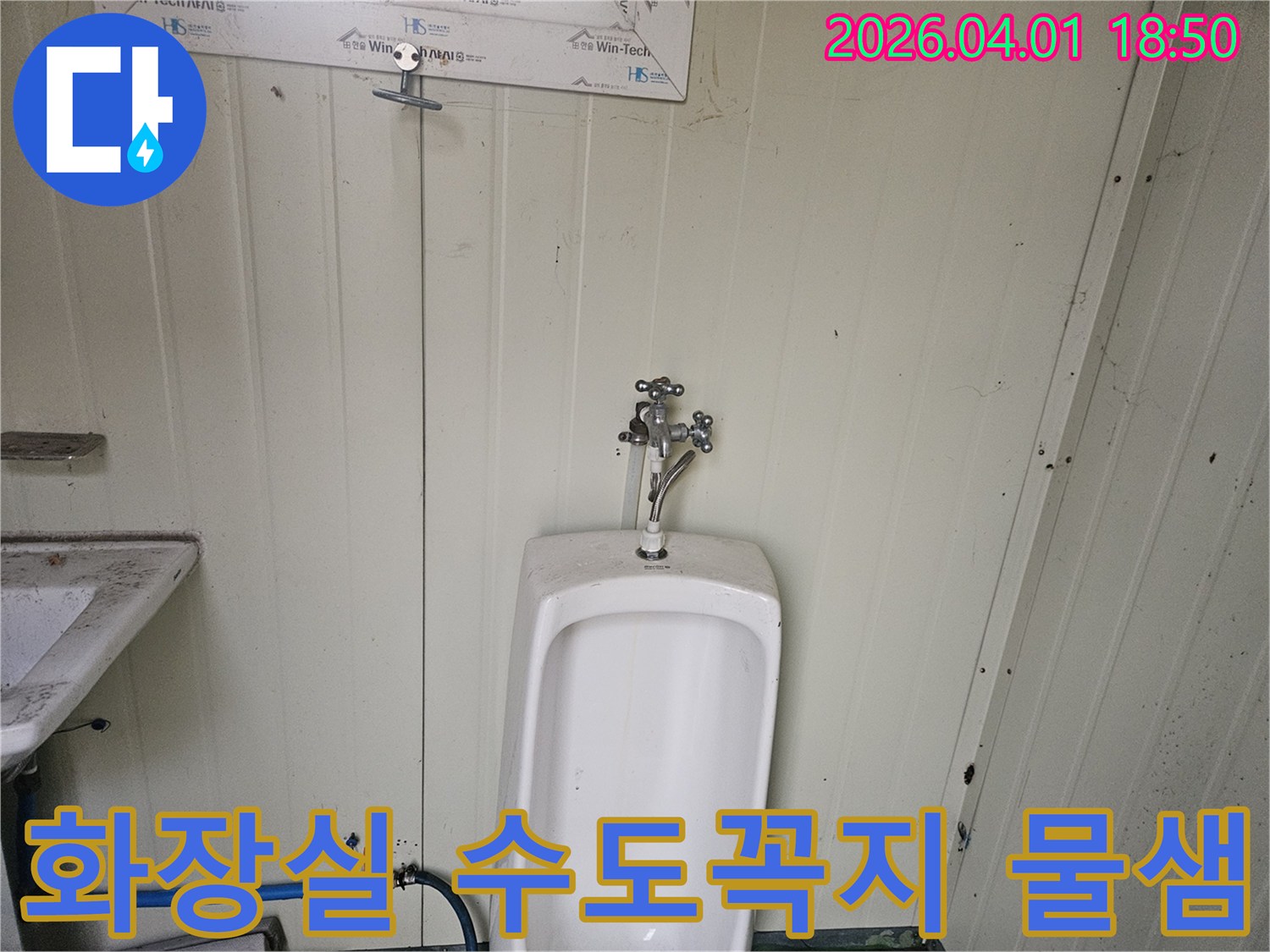 임시 시설물 내 소변기 상단에 위치한 수도꼭지와-하단 급수관에서 물이 새는 상황을 나타내는 사진