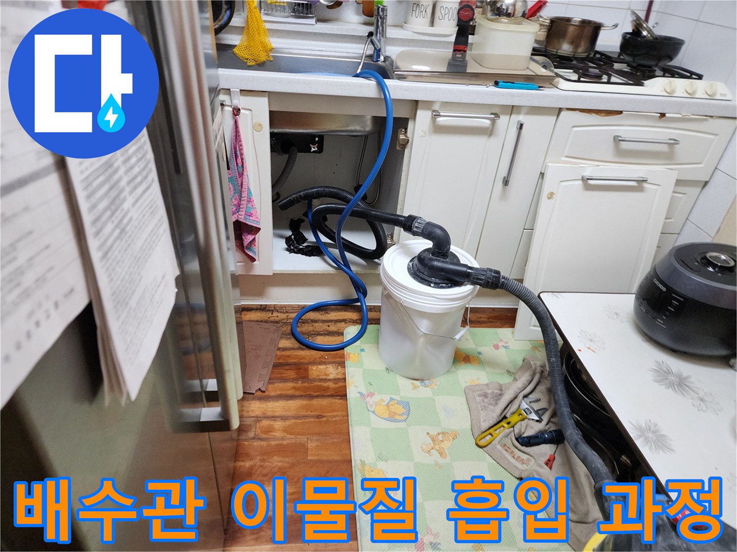 싱크대 하부 배관 연결 부위에 설치된 석션 호스와 수거통 모습