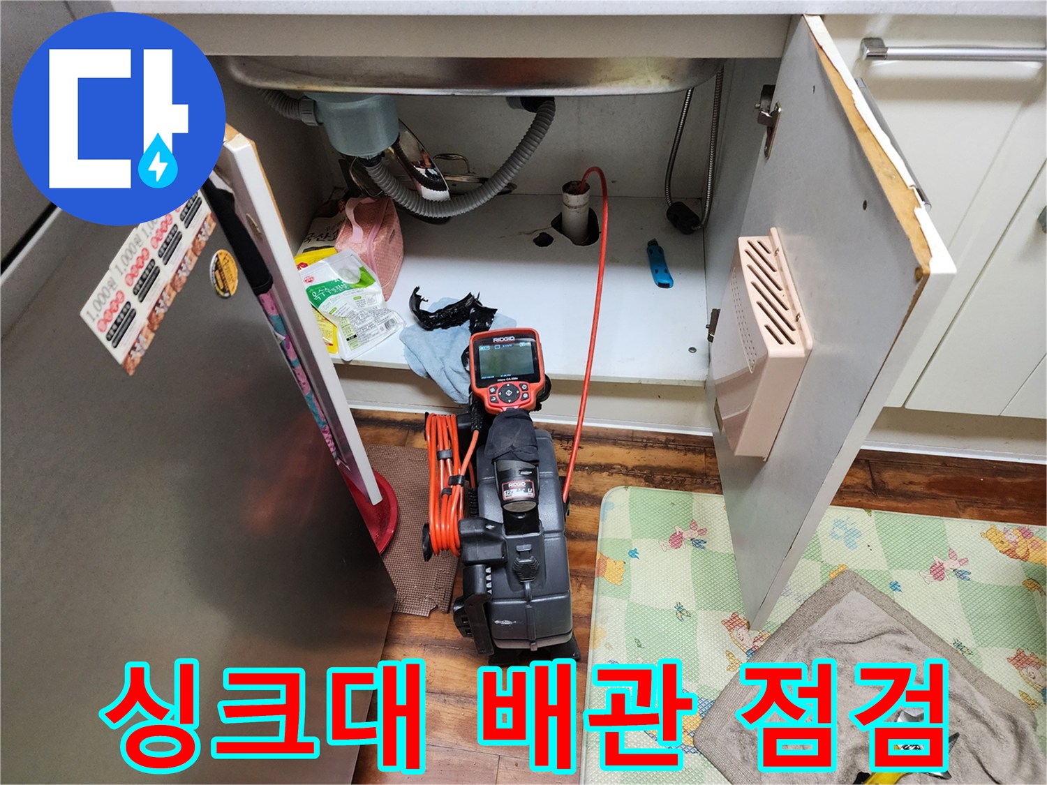 주방 싱크대 하부장 내부의 배수 호스와 점검 장비 모습