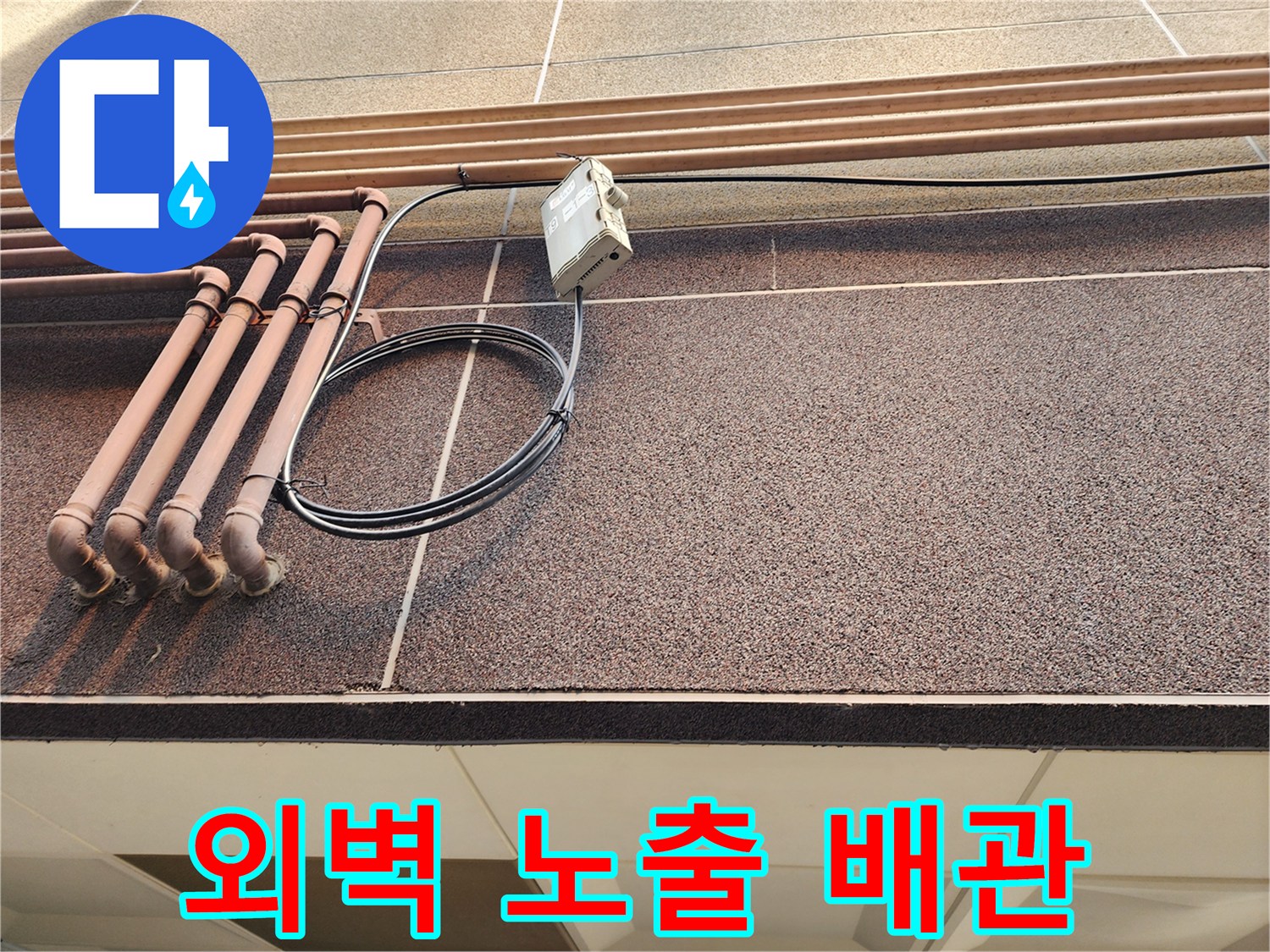 건물 외벽의 갈색 배관과 전기 장치 연결 부위