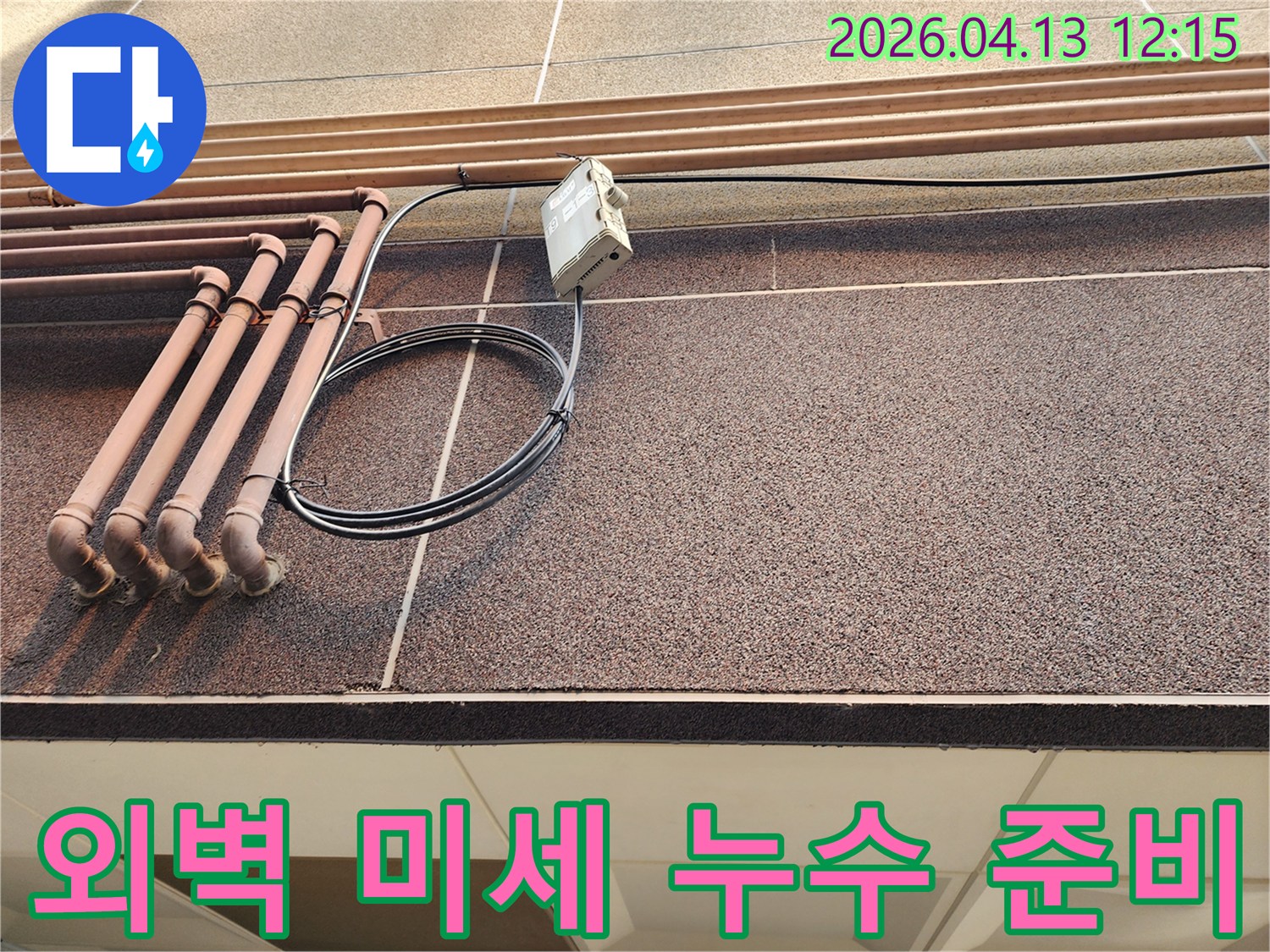 건물 외벽의 배관 주변에서-미세한 누수를 탐지하기 위한 준비 작업을 진행하는 모습입니다.