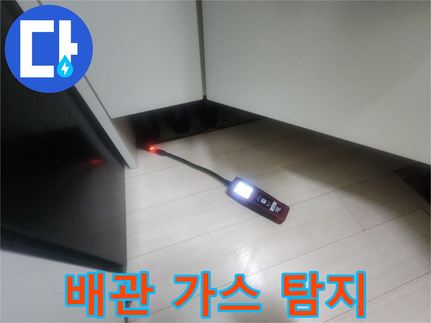 어두운 싱크대 하부 공간에 배치된 휴대용 가스 탐지 장비-