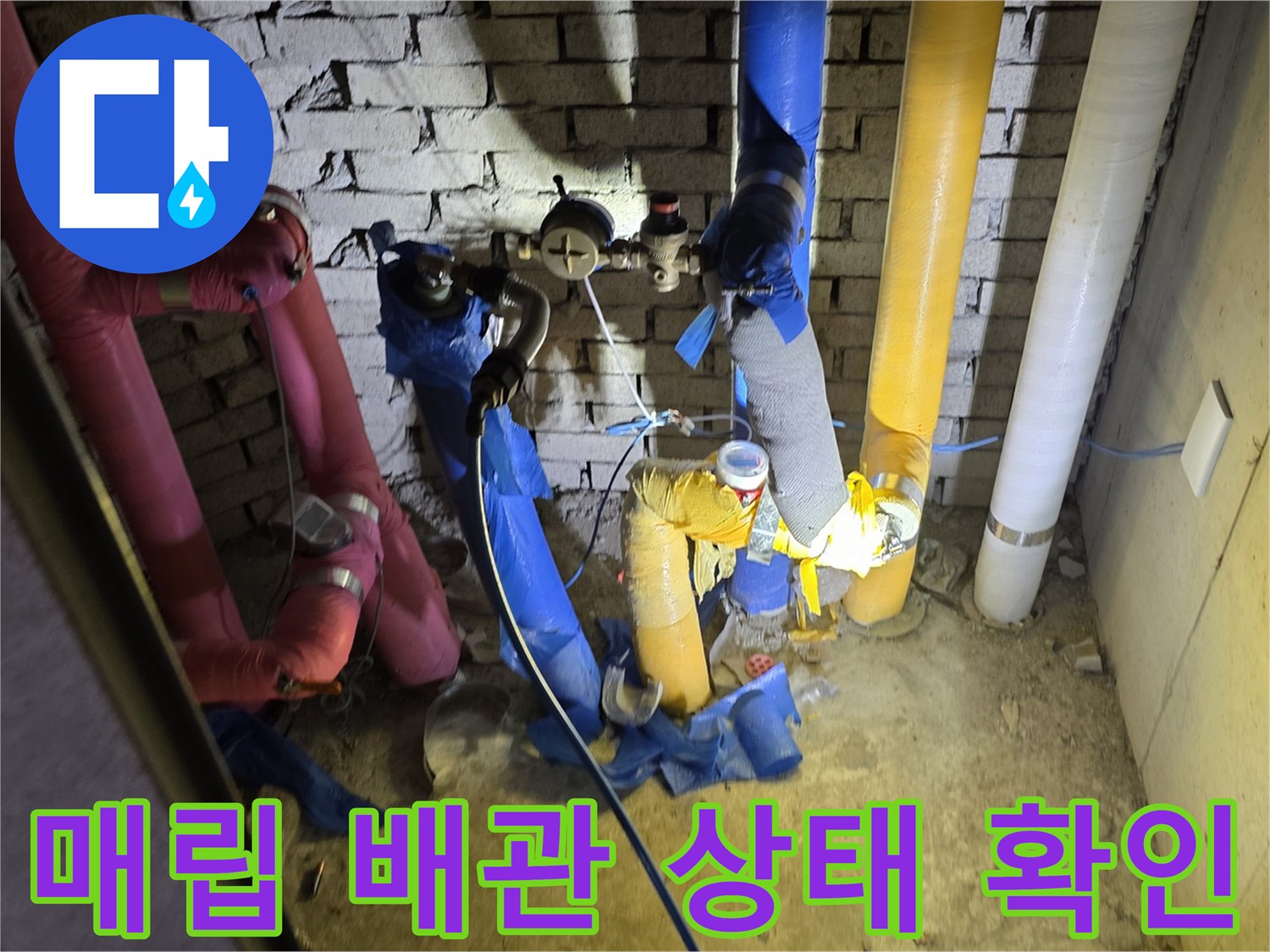 벽면 내부의 다양한 색상 배관들과 점검 중인 작업자