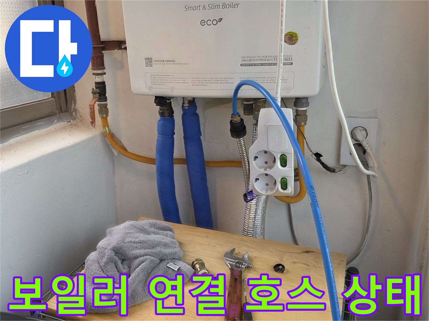 파란색 호스와 은색 주름관이 연결된 보일러 하단부