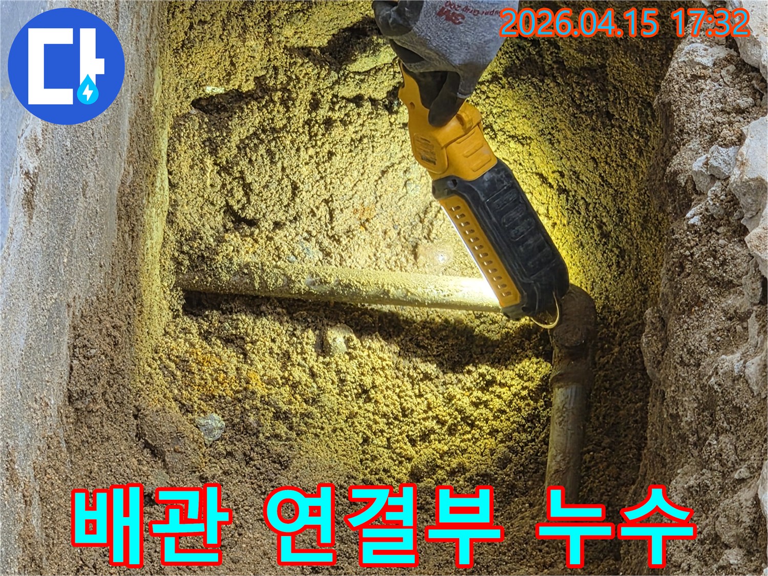 전문가가-손전등으로-땅속에-묻힌-배관의-연결부에서-발생하는-누수-여부를-정밀하게-확인하고-있습니다.