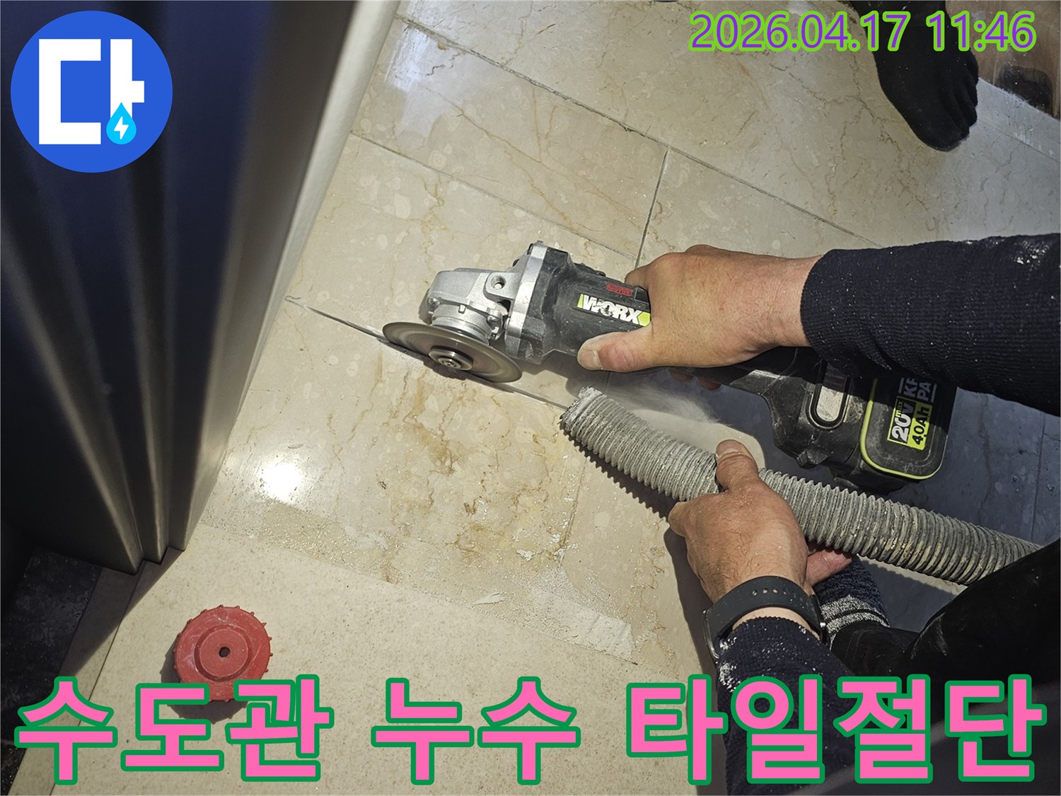 수도관 누수 진단을 위해 작업자가 그라인더로 바닥 타일을 절단하고-있으며-동시에-흡진기로-먼지를-제거하여-깨끗한-작업-환경을-유지하는-모습입니다.