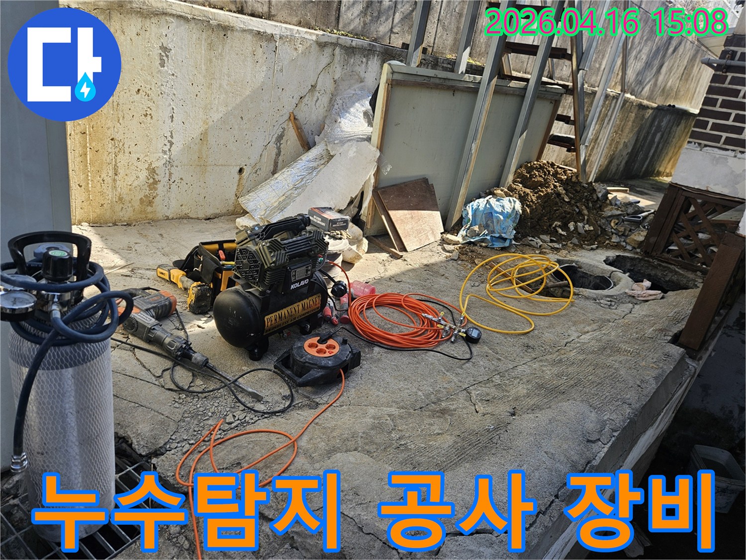 누수 공사 현장에서-에어 콤프레셔와-함마드릴-호스-전선릴 등-다양한 작업 도구들이-콘크리트 바닥 위에-준비되어 있는 모습