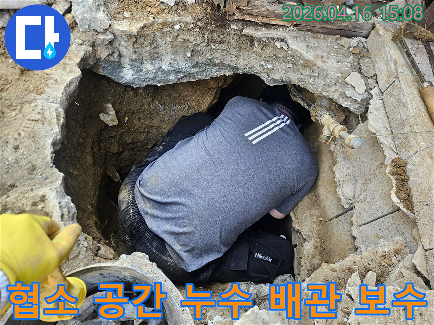 누수 전문 기술자가-좁고 깊은 구덩이 안에서-배관 누수 지점을-세심하게 보수하는 작업 현장