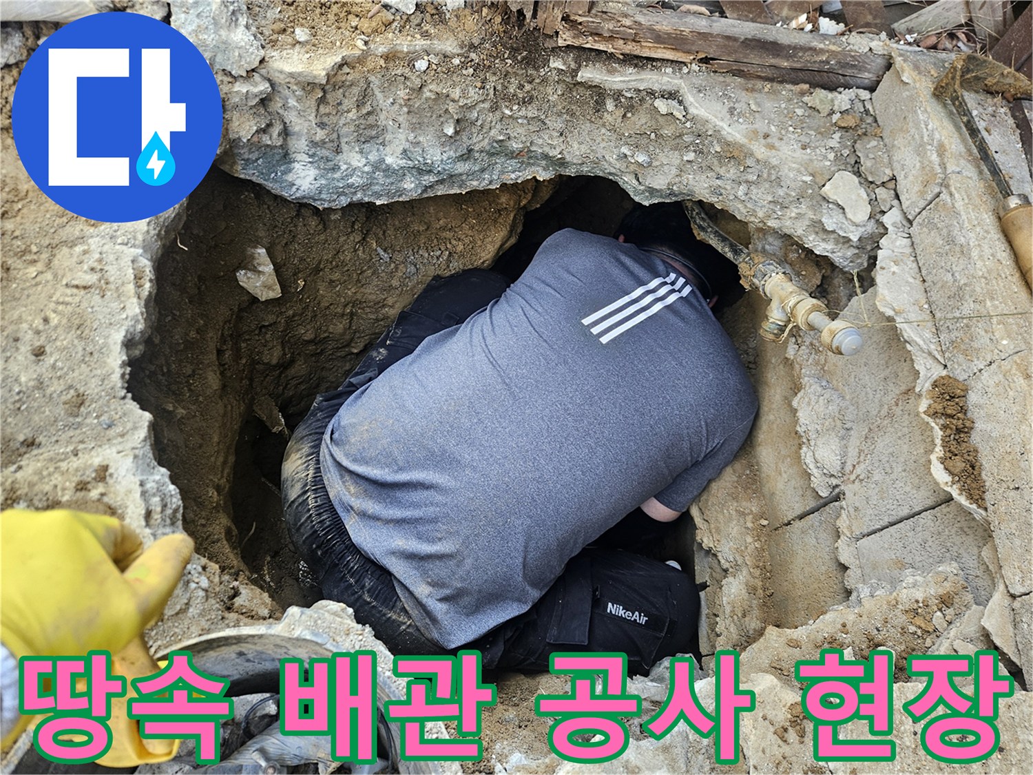 전문 배관 기술자가-땅속에 매설된 배관을-설치하거나 보수하기 위해-좁은 공간에서 작업하는 모습