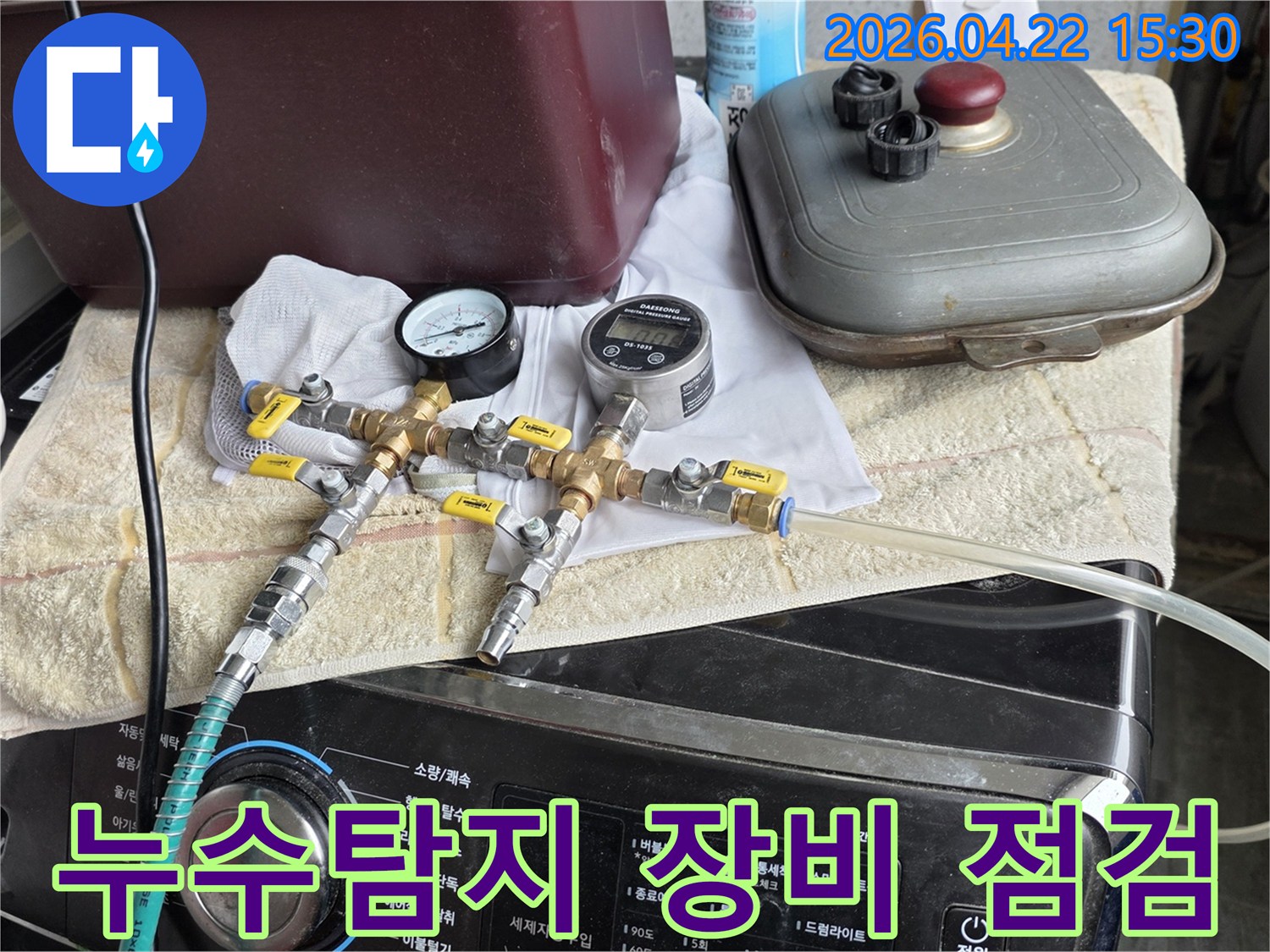 누수 탐지를 위해-압력계와 유량계가 연결된-전문 장비의-정상 작동 여부를-점검하는 장면입니다.