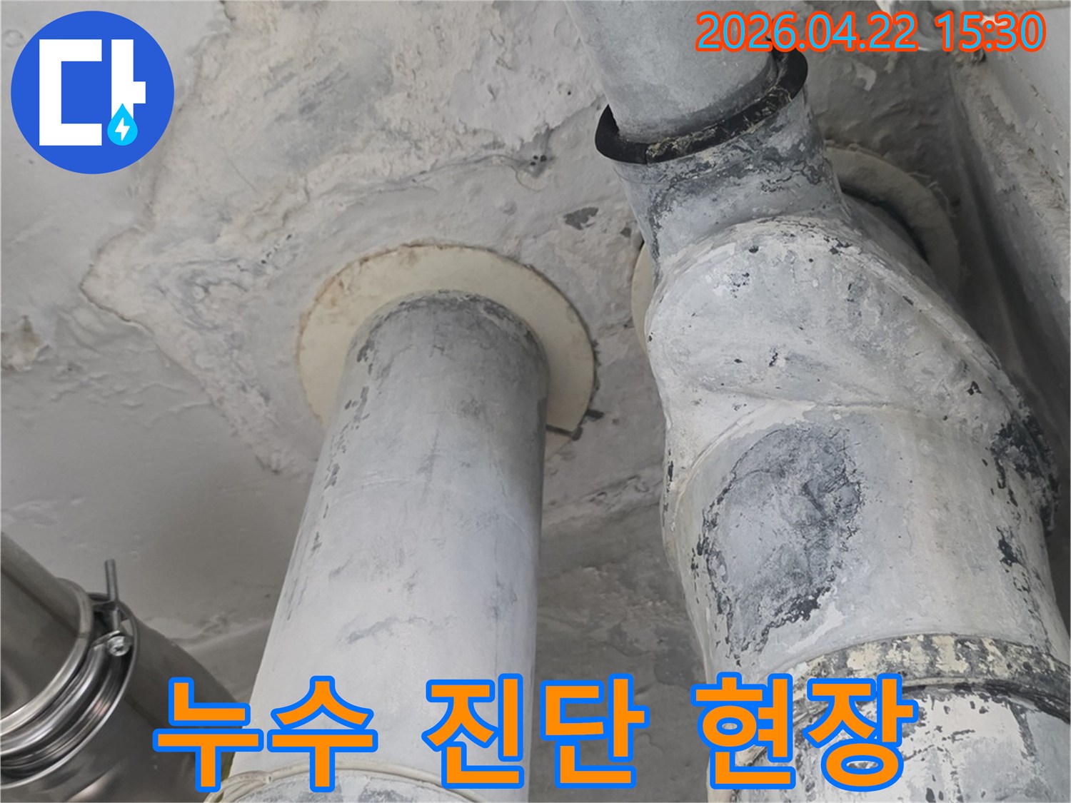 아파트 천장 배관 주변에서-누수 진단을 위해 촬영된 사진으로-벽면의 변색과 습기 흔적을 보여줍니다.