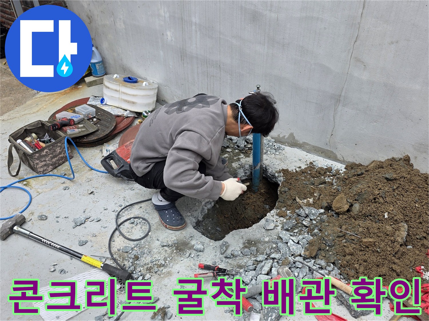 공사 중인 바닥의 깨진 콘크리트와 노출된 파란색 급수 배관