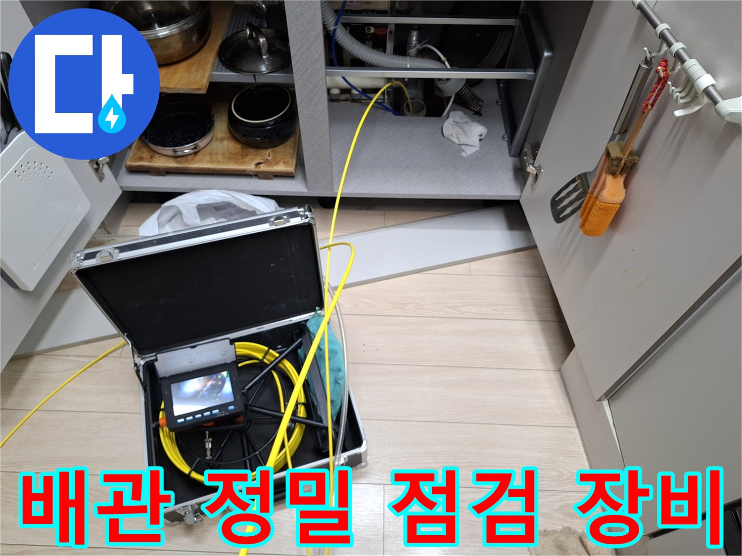 싱크대 하부에서 사용 중인 디지털 압력계와 내시경 카메라 장비 세트