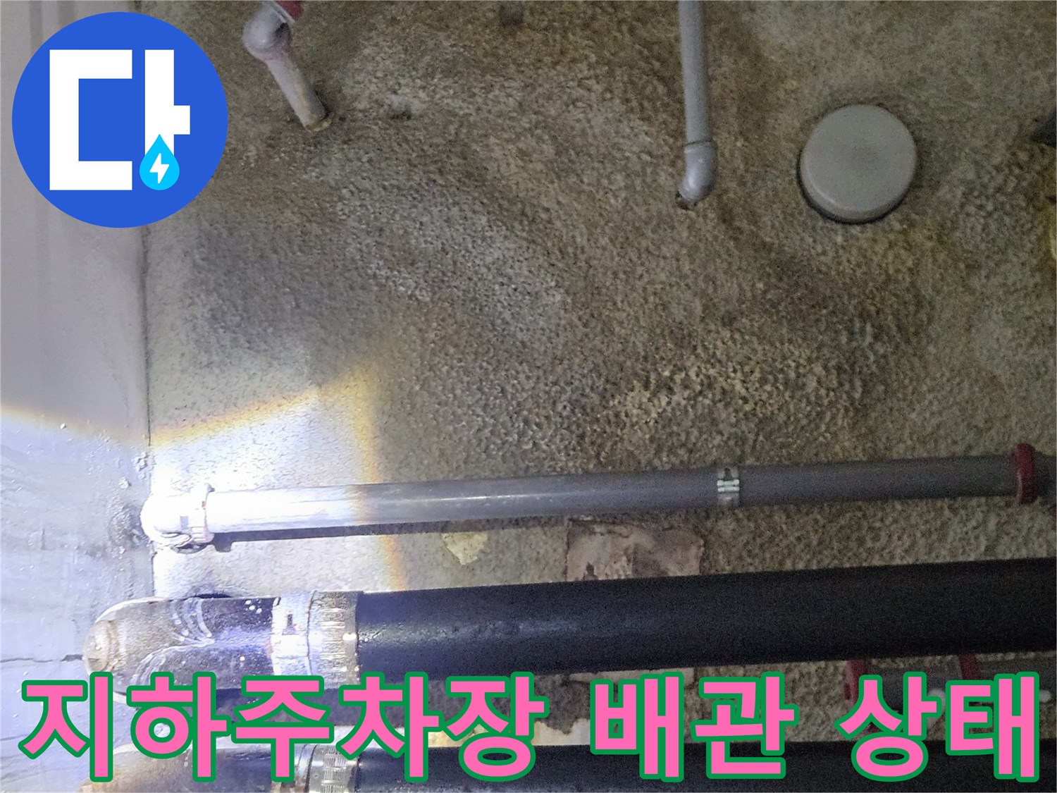지하 주차장 천장에 설치된 검은색과 회색 배관의 모습입니다.