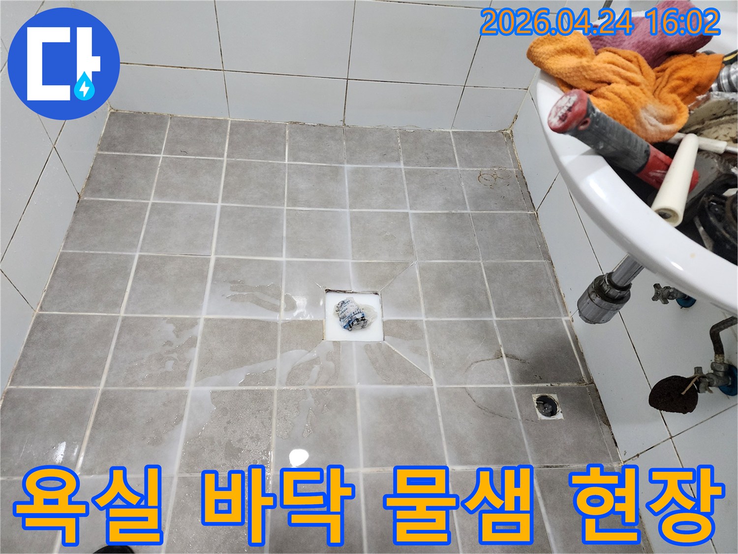 욕실 바닥 타일 위에-물이 흥건하게 고여-누수 문제를 보여주는-현장 점검 사진입니다