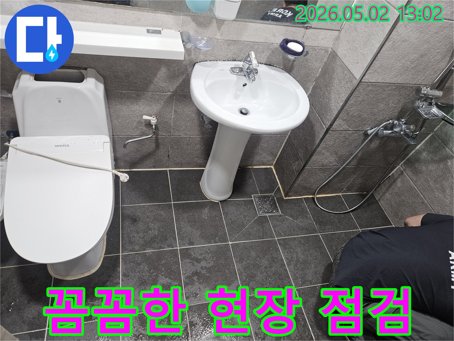 이 이미지는-욕실 바닥의-젖은 타일과-변기-세면대 주변의-물기 흔적을 보여주며-누수 전문가의-꼼꼼한 현장 점검 과정을-상세히 나타냅니다.
