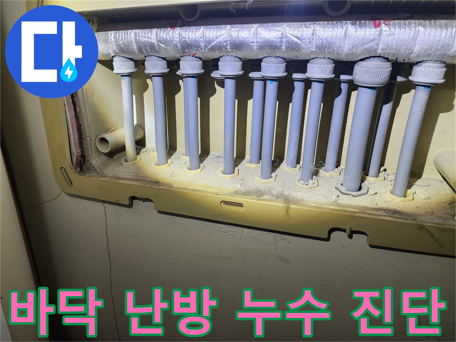난방 분배기 하단에 위치한-배관 연결부에서 발생한-누수 흔적을-전문가가 정밀하게 확인하고 있습니다.