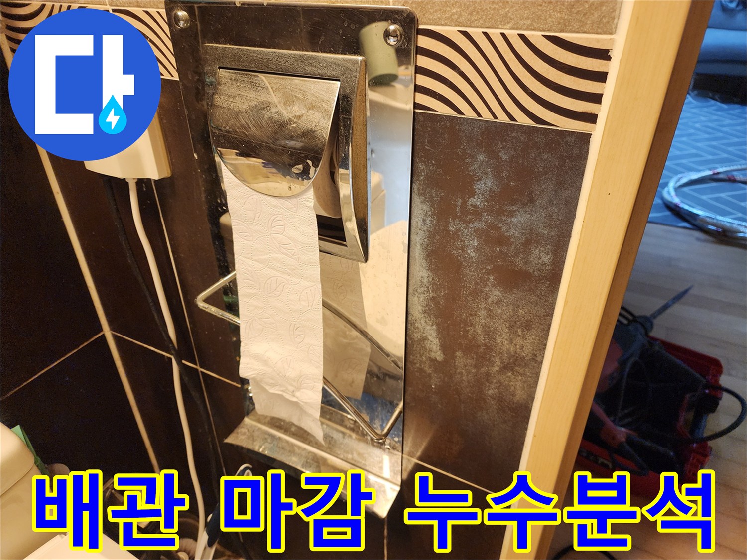 욕실 벽면의-휴지걸이와-그 주변 타일의-오염 상태-그리고-배관 마감부를-면밀히-살펴보며-누수 흔적을-분석하는-장면입니다.