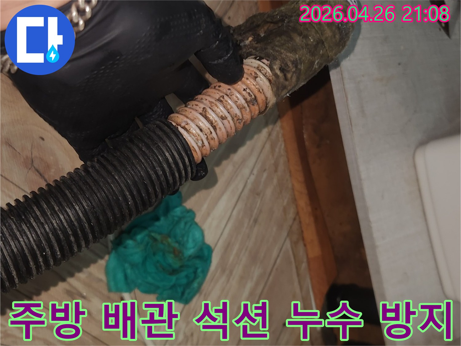 검은색 장갑을 낀 작업자가-오염된 주방 배수 호스를-석션 장비로 깨끗하게 청소하여-누수를 사전에 방지하는 모습