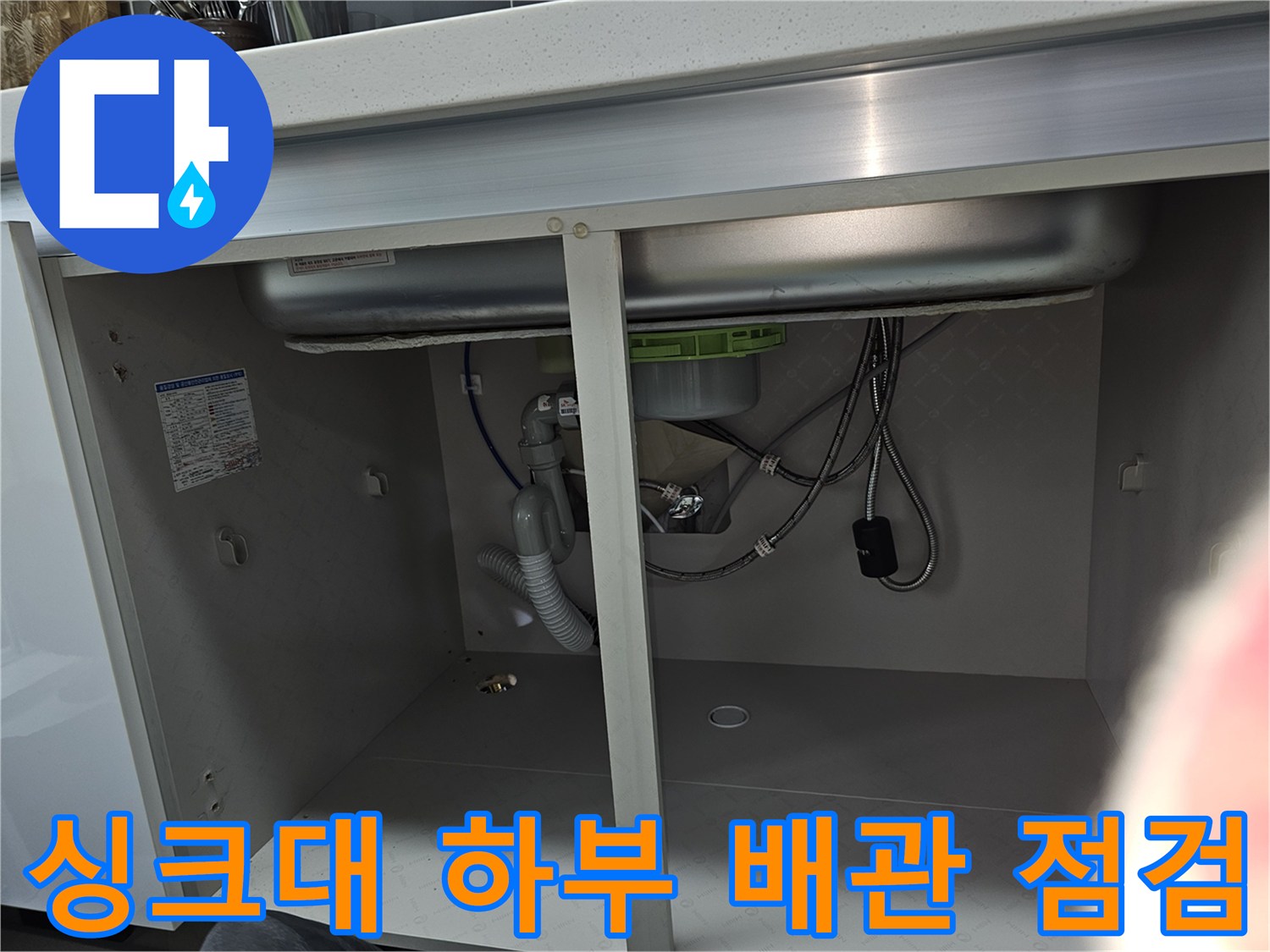 이 이미지는 주방 싱크대 하부의 배관과 배수구 연결 상태를 보여줍니다-누수 점검을 위한 내부 모습입니다.