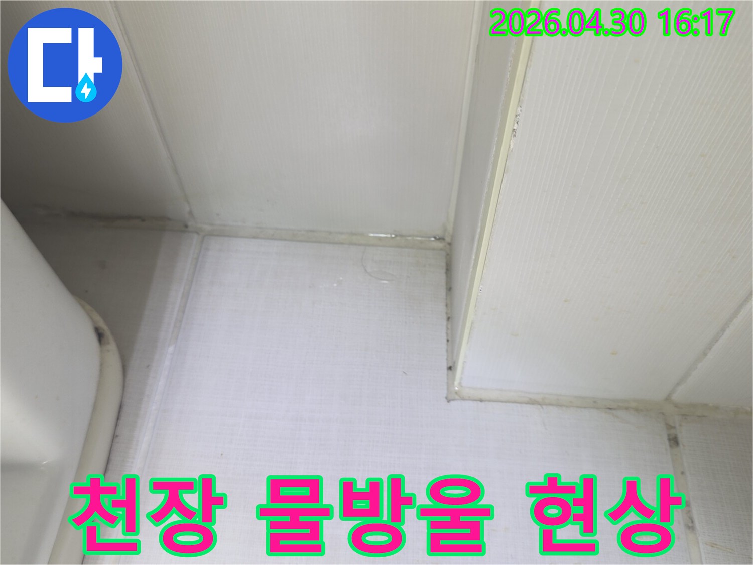 천장과 벽의 접합부에서 물방울이 맺히고-벽지가 젖어있는 상태를 보여주는-누수 발생 현장의 클로즈업 이미지