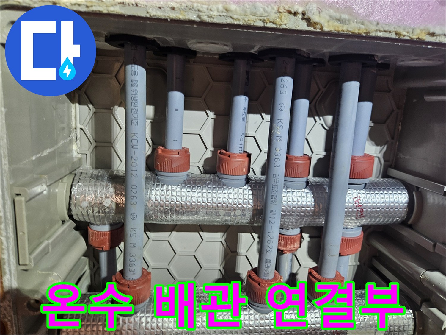 아파트 온수 배관 점검-다수의 회색 파이프와 빨간색 캡으로 이루어진 구조