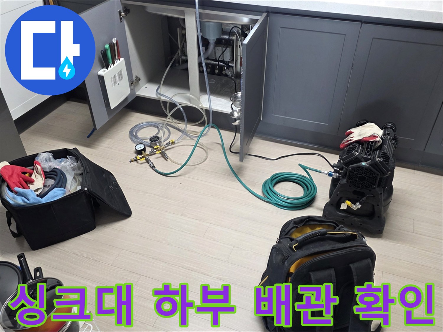 싱크대 아래쪽 점검구를 열어 배관 상태를 육안으로 검사하는 장면입니다.