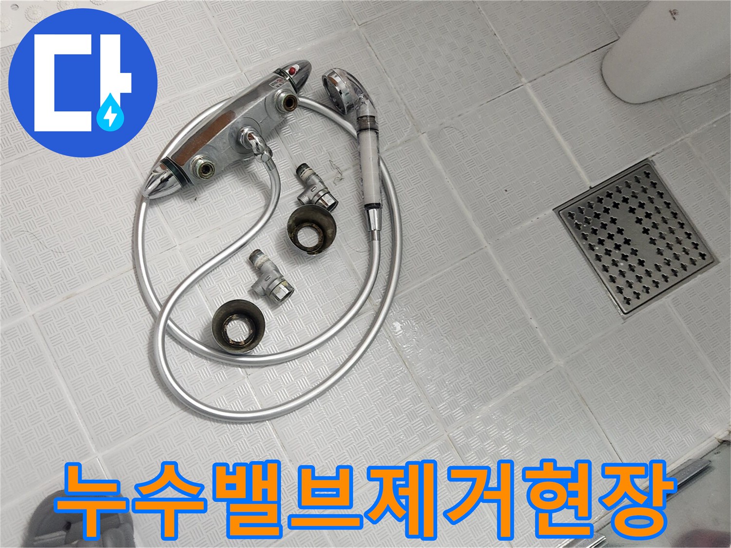 욕실 바닥에 놓인 분리된 샤워기 밸브와 호스-누수 원인 제거를 위한 작업 현장