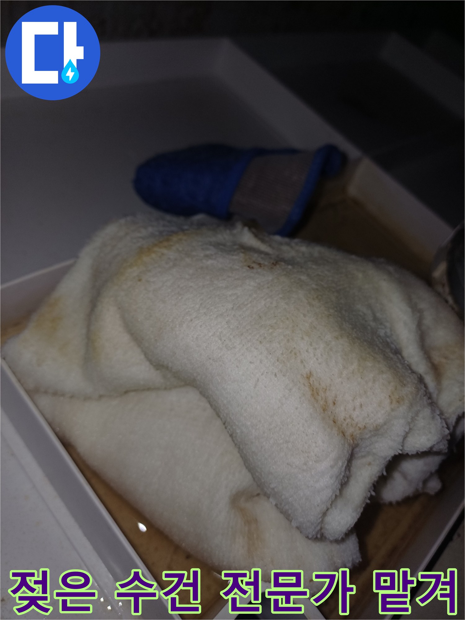 물에 젖어 얼룩이 생긴 수건이 상자 안에 놓여 있는-누수 피해가 진행 중임을 보여주는 현장 사진입니다.