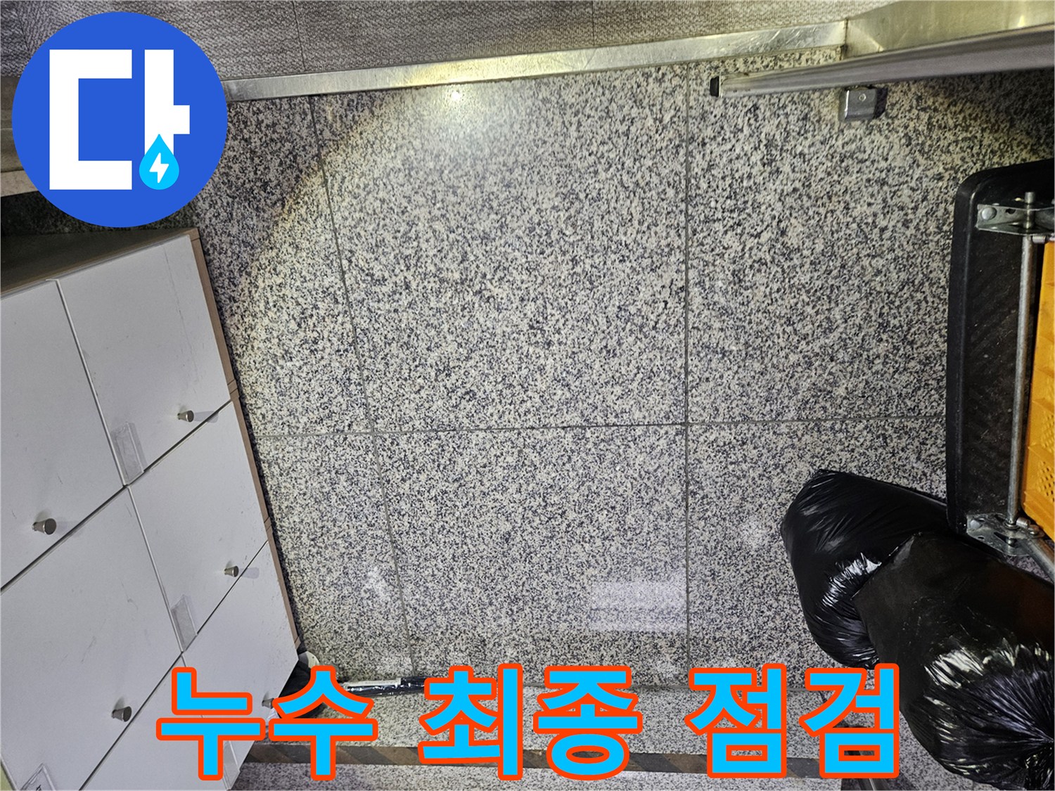 포천 상가 건물에서-바닥 타일의 젖은 부분을 발견하여-누수 전문가가 현장을 면밀히 살피는-초기 진단 단계입니다