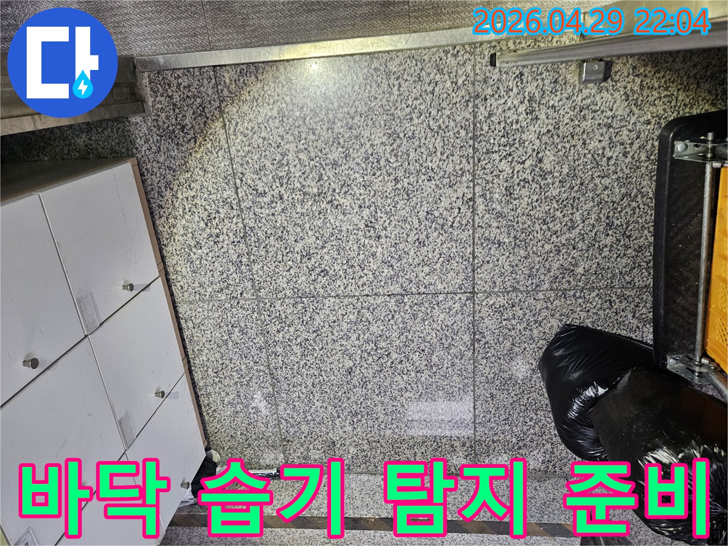 포천 아파트의 바닥 타일에서-누수로 인한 물기 흔적을 발견하고-정확한 누수 지점을 찾기 위한-전문가의 면밀한 점검이 이루어지고 있습니다