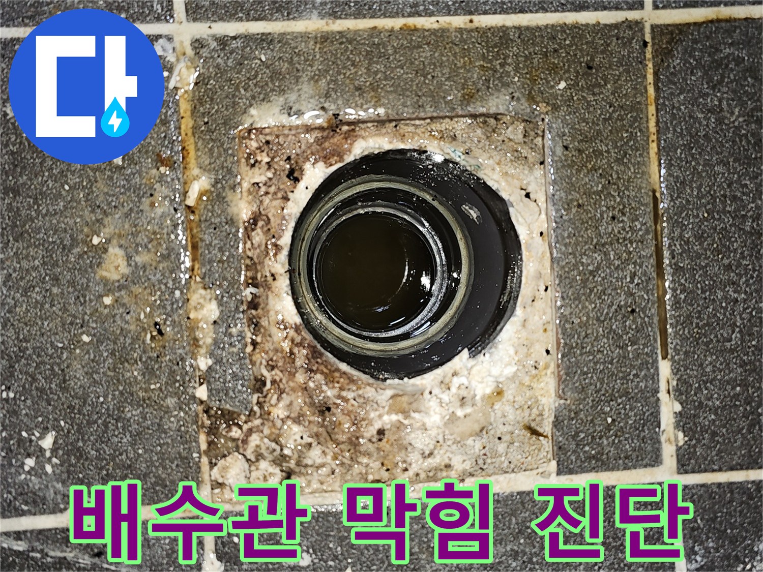 배수구에서 오수가 역류하여-바닥에 고여있는 모습을 보여주는-심각한 배관 막힘 현장의 사진입니다.