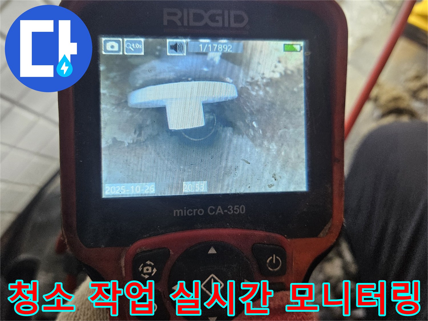 이 이미지는-전문 엔지니어가-배관 청소 작업 중에-내시경 카메라를 사용하여-배관 내부의-이물질 제거 과정을-실시간으로 모니터링하는-모습을 보여줍니다.